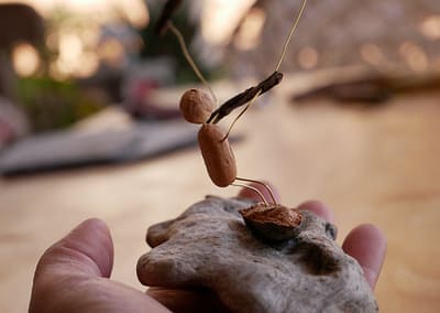 Baumperle als Figur auf einem Treibholz