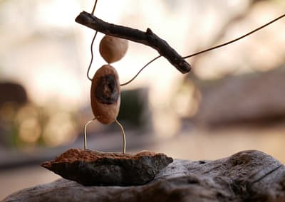 Baumperle als Figur auf einem Treibholz